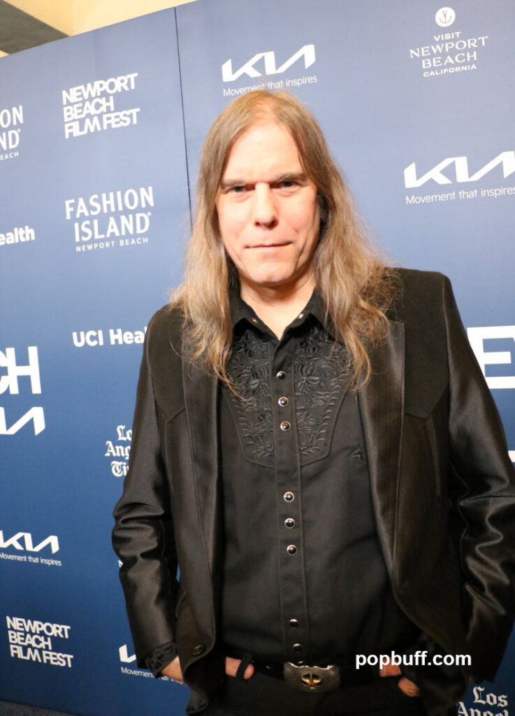 Composer Graham Reynolds of Blue Moon posed on the blue carpet at the Newport Beach Film Festival 2025 - Popbuff.com
